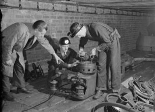 Classic British workwear clothing,1944 photo of Men in work clothing at the British Training School Sheffield, West Riding, Yorkshire, England, UK, using American Mining Equipment,