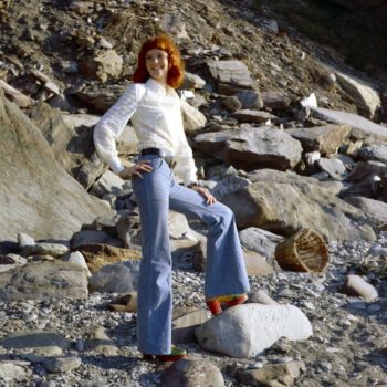 Vintage clothing online- Rehead model in white blouse and bell bottom jeans, Devon, UK, 1970s.