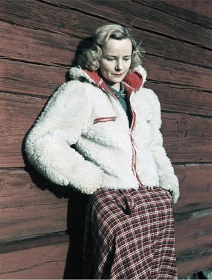 The 40s fashion, Woman wearing white fleece jacket and checked skirt leaning against wall, Photo by Gunnar Lundh. 1941