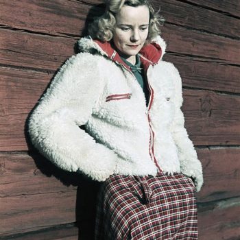 The 40s fashion, Woman wearing white fleece jacket and checked skirt leaning against wall, Photo by Gunnar Lundh. 1941