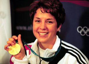 Gold shell suit, Nancy Johnson holding up her gold medal.