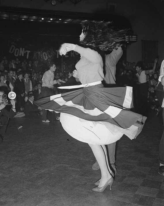 Girl in wide circle skirt twirling at rock' n roll dance, 1950s Girl in wide circle skirt twirling at rock' n roll dance, 1950s
