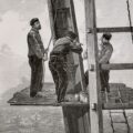 French chore jackets with construction workers standing on an elevated platform on the Eiffel Tower, 1889