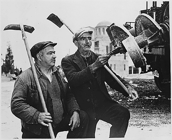 Two workmen examine earth boring equipment Two workmen examine earth boring equipment