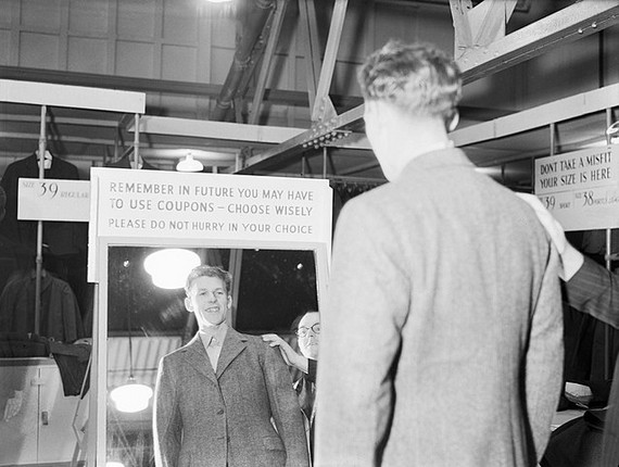 Aircrew training cadet views his new demob suit in a standing mirror with a placard above it saying "Remember in future you may have to use coupons - choose wisely. Please do not hurry in your choice" at a civilian clothing centre in Wembley, 17 October, 1944 Aircrew training cadet views his new demob suit in a standing mirror with a placard above it saying "Remember in future you may have to use coupons - choose wisely. Please do not hurry in your choice" at a civilian clothing centre in Wembley, 17 October, 1944