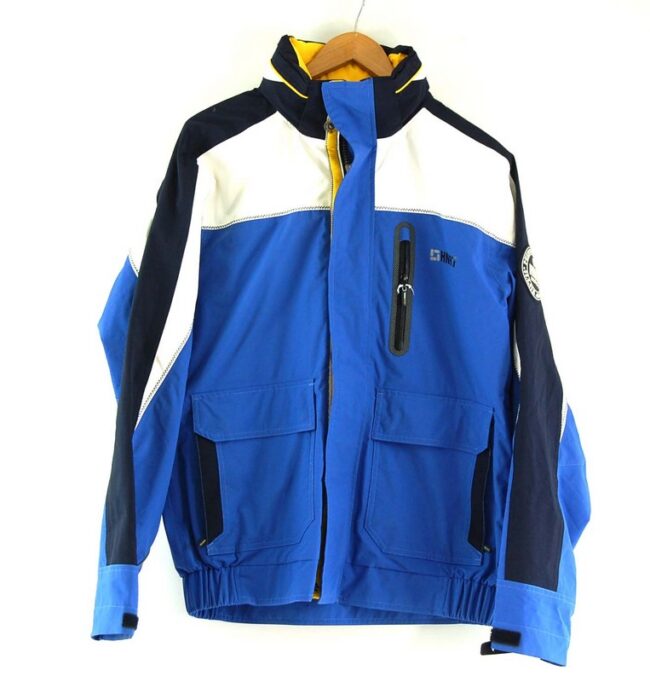 Human Nature Waterproof Jacket. Features a blue body with white and dark blue panels, 'HN97' logo at right side chest and 'HN 97 Nautical' patch on right sleeve and two large front patch pockets. Has front zip opening with popper flap, a funnel collar with fold away hood, cuffs with velcro straps and an elastciated waitband. Fully lined with one inner pocket. Size medium.