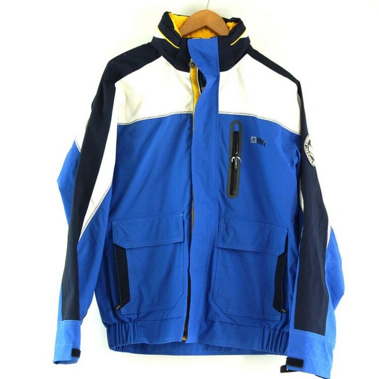 Human Nature Waterproof Jacket. Features a blue body with white and dark blue panels, 'HN97' logo at right side chest and 'HN 97 Nautical' patch on right sleeve and two large front patch pockets. Has front zip opening with popper flap, a funnel collar with fold away hood, cuffs with velcro straps and an elastciated waitband. Fully lined with one inner pocket. Size medium.